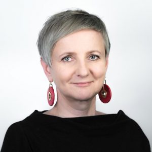 uśmiechnięta kobieta z dużymi czerwonymi kolczykami w kształcie pączków