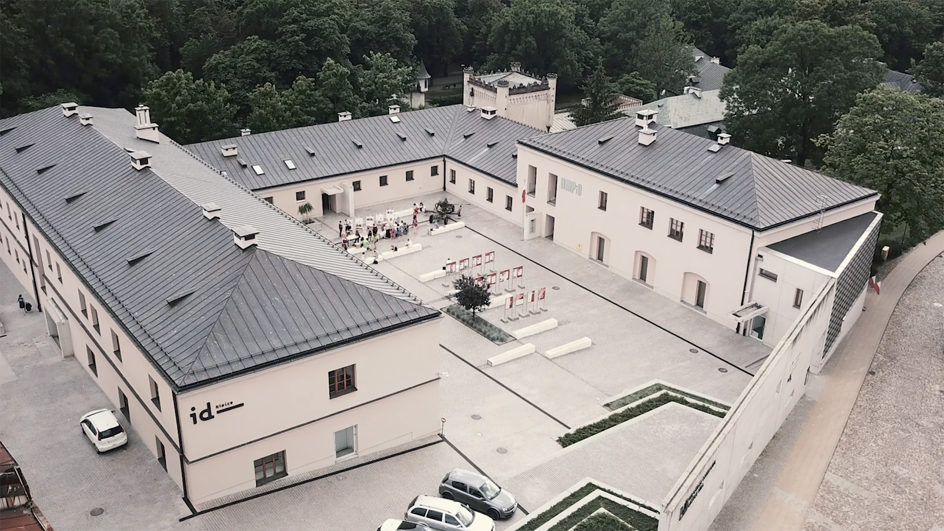 dziedziniec budynku w kształcie litery U o bielonych ścianach